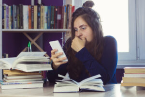 A student looks at her phone instead of studying_NCLEX Classes